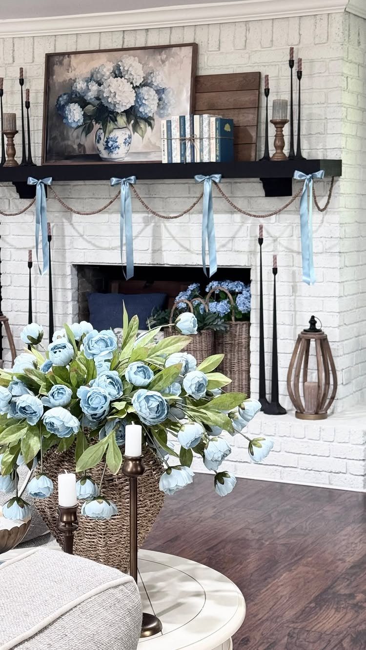 12 Blue White Living Room Ideas with Photos and Styling Tips 6 Painting of blue hydrangeas displayed above a black fireplace mantel with blue ribbons.