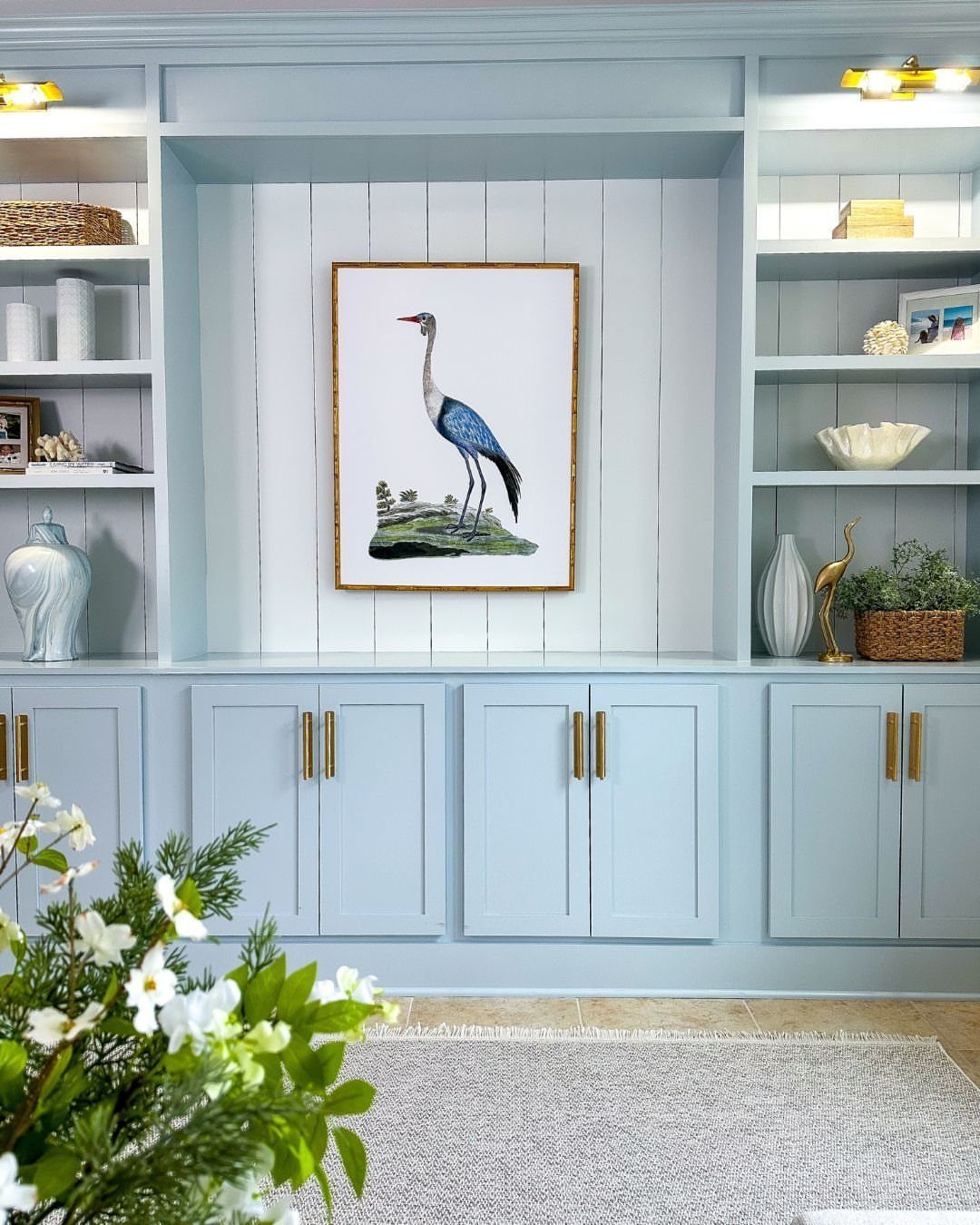 12 Blue White Living Room Ideas with Photos and Styling Tips 13 Light blue built-in shelving unit with gold hardware and a crane painting.