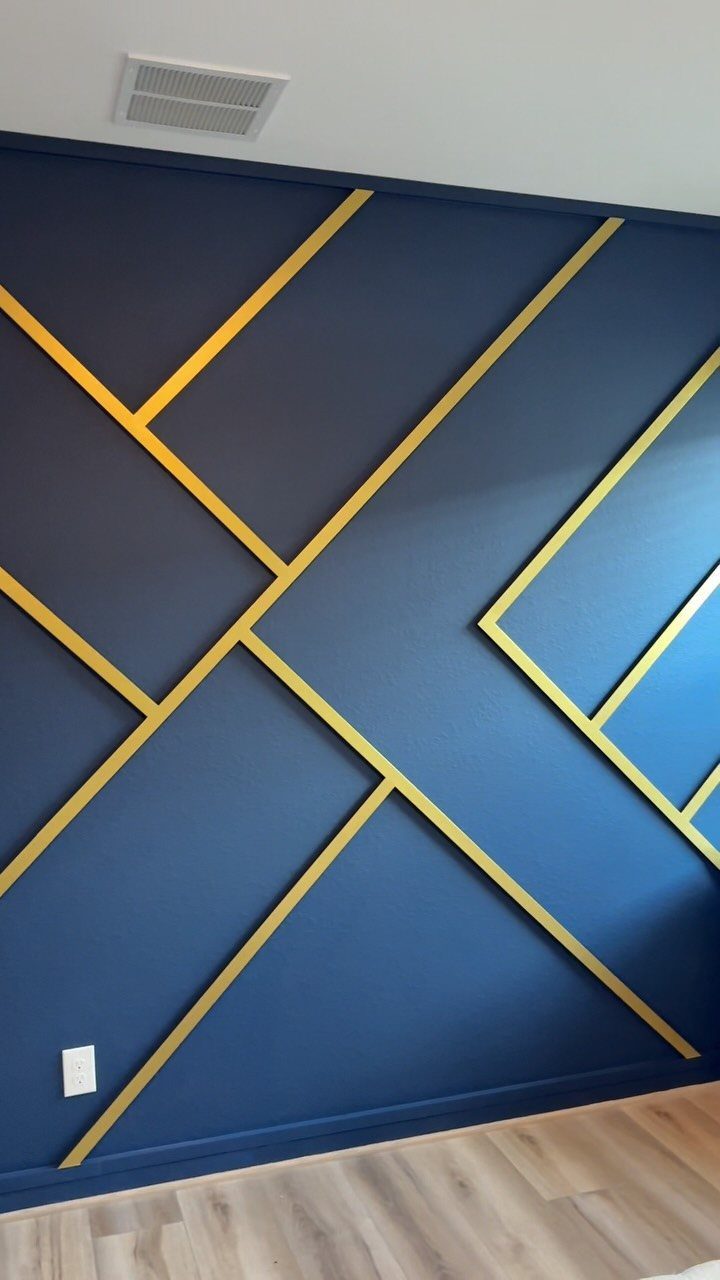 Dark blue accent wall with gold geometric strips and light wood flooring