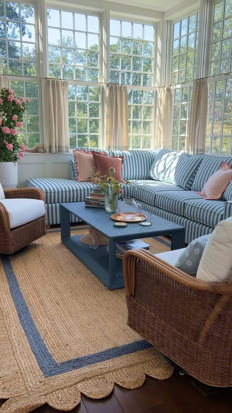 Blue and white striped sectional sofa with wicker chairs in a bright sunroom.