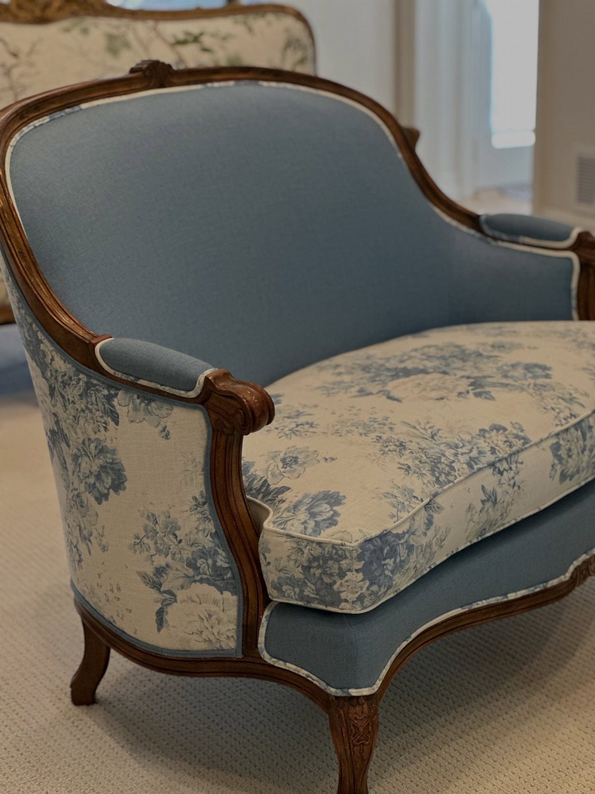 Classic armchair with light blue upholstery and blue floral patterned seat cushions.