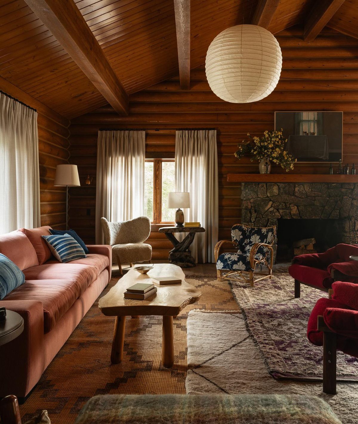 Rustic log walls in a living room with blue patterned seating and wooden furniture.